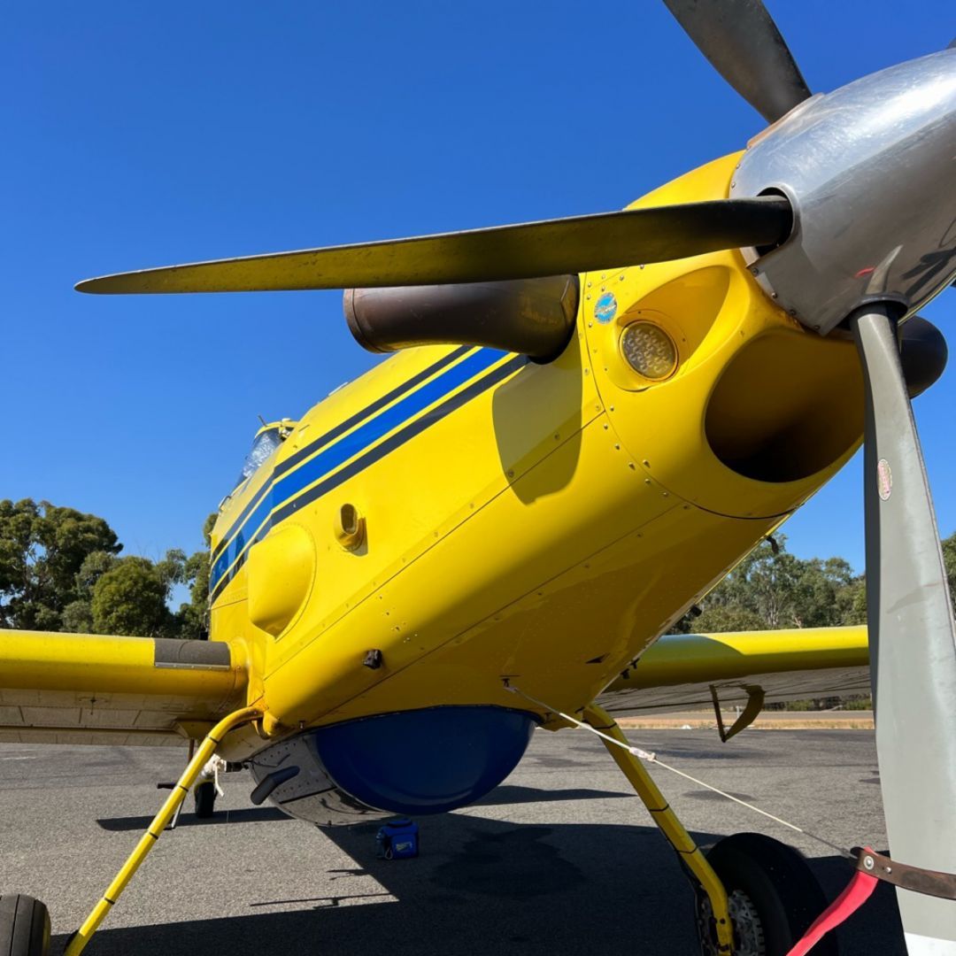 low angle photo of the nose of an AT802 firebombing aircraft showing part of the propeller and the landing gear