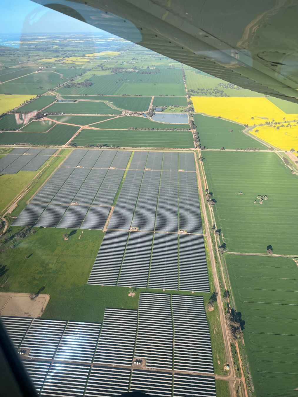 Arrays of solar panels on flat green farmland