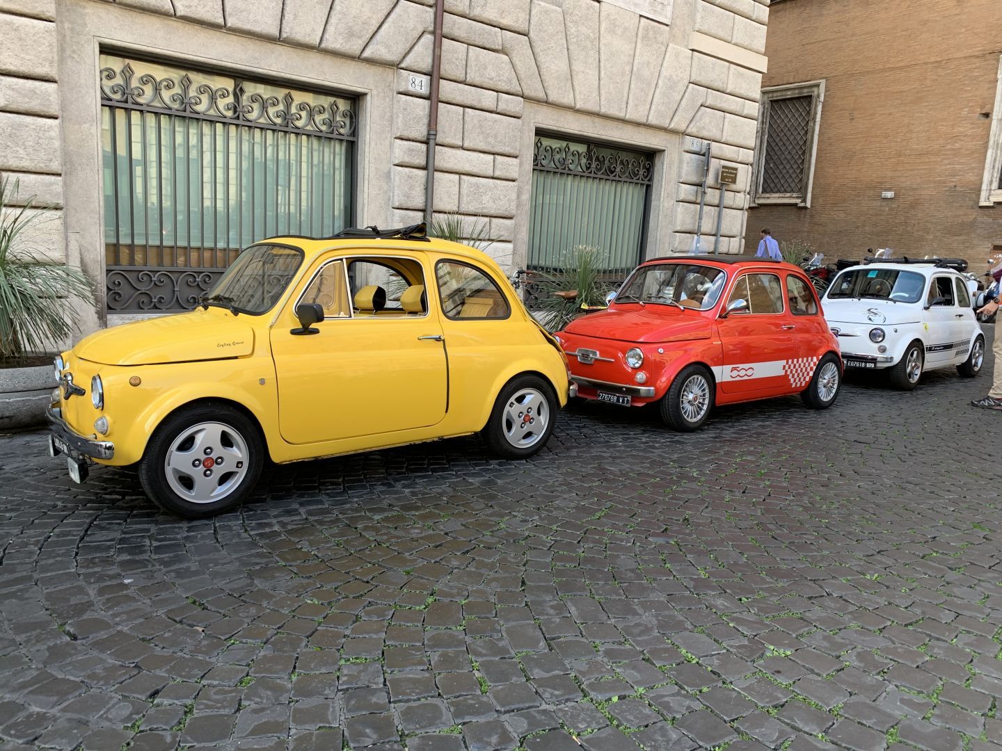 3 Fiat 500 cars, yellow, red and white
Parked together in a cobblestone street