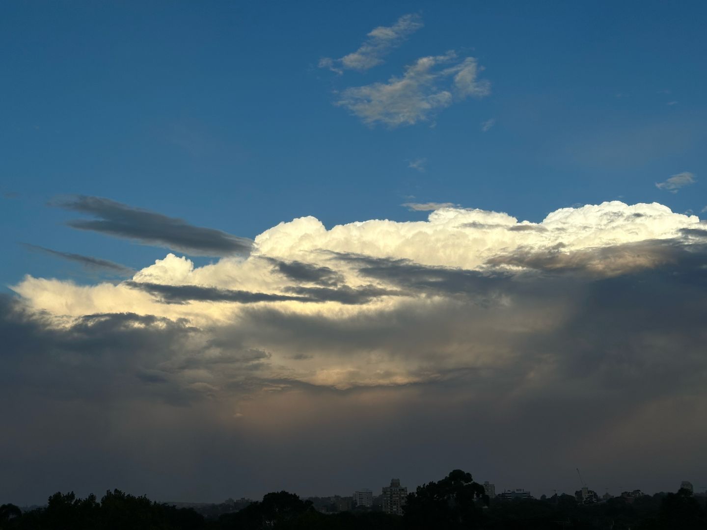 Sunlit clouds just before sunset, layers of darker clouds below