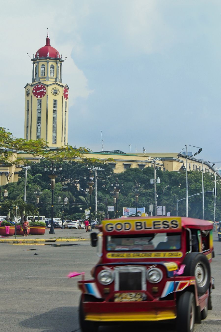 Manila city hall is in the background while theres a moving jeep in the foreground.